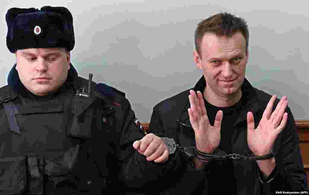 Kremlin critic Aleksei Navalny, who was arrested during a March 26 anticorruption rally, gestures as he wears two pairs of handcuffs during an appeal hearing at a court in Moscow. A Russian court on March 27 sentenced him to 15 days behind bars after ruling that he had resisted police. (AFP/Kirill Kudryavtsev)