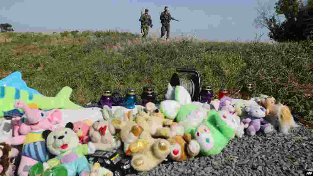 Orsýetçi ýaragly pitneçiler MH17 uçarynyň ýykylan ýerinden geçip barýarlar. Ukraina, Donetsk regiony. (AFP/Aleksey Filippov)