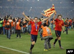 Történelmi öröm 2010-ből: A spanyol középpályás Xavi (b) és a spanyol védő Carles Puyol fut a 2010-es labdarúgó-világbajnokság Hollandia–Spanyolország-döntőjét követő tiszteletkörön 2010. július 11-én a Soccer City stadionban, Sowetóban, Johannesburg külvárosában