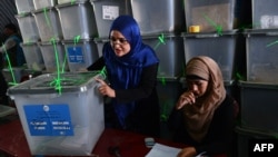 Afghan election commission workers prepare to cut open the seals to a box containing ballot papers for an audit of the presidential runoff votes at a counting center in Kabul on July 17.