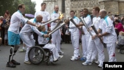 Torch bearers carry the Paralympic flame outside Westminster Abbey in London, 29Aug2012