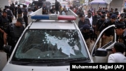 Officers examine a damaged police vehicle after a recent attack (file photo)