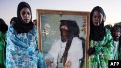 Women from the nomadic Tuareg tribe in traditional dress hold a portrait of Libyan leader Muammar Qaddafi during the 16th International Ghat Festival in southwest Libya in February 2010.