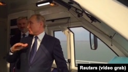 Президент России Владимир Путин стоит в кабине машиниста первого поезда, направляющегося по Керченскому мосту из Керчи в российский город Тамань. 23 декабря 2019 года