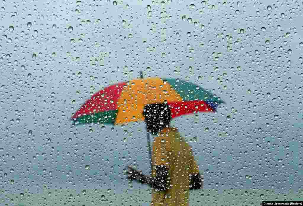 A man carrying an umbrella is seen through a window covered with rain drops during a wet day in Colombo, Sri Lanka. (Reuters/Dinuka Liyanawatte)