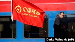 Рабочий на участке железной дороги, реконструкция которой позволит соединить Будапешт с Белградом. На флаге — логотип китайской железнодорожной компании.