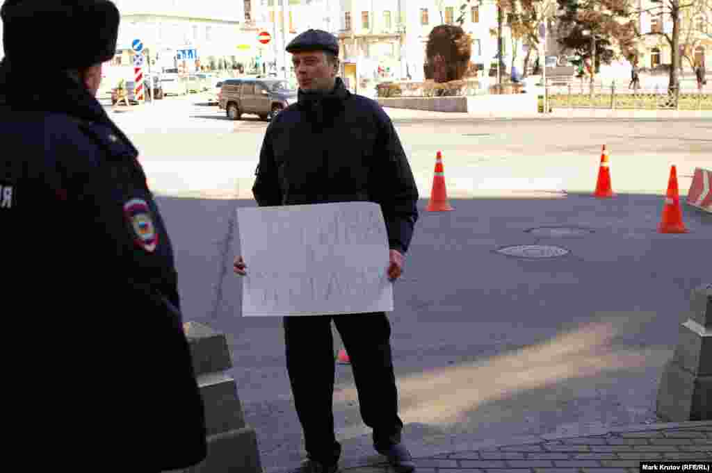 Мужчина с плакатом &quot;Путина в отставку&quot; внезапно появился в нескольких метрах от пикетчиков и тут же был задержан полицией. Был ли он провокатором, чья роль - нарушить правила проведения одиночных пикетов, осталось неясным