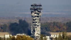 A Ukrainian national flag flies at top of a badly damaged traffic control tower as smoke rises after shelling at the Donetsk Sergey Prokofiev International Airport in Donetsk (file photo)