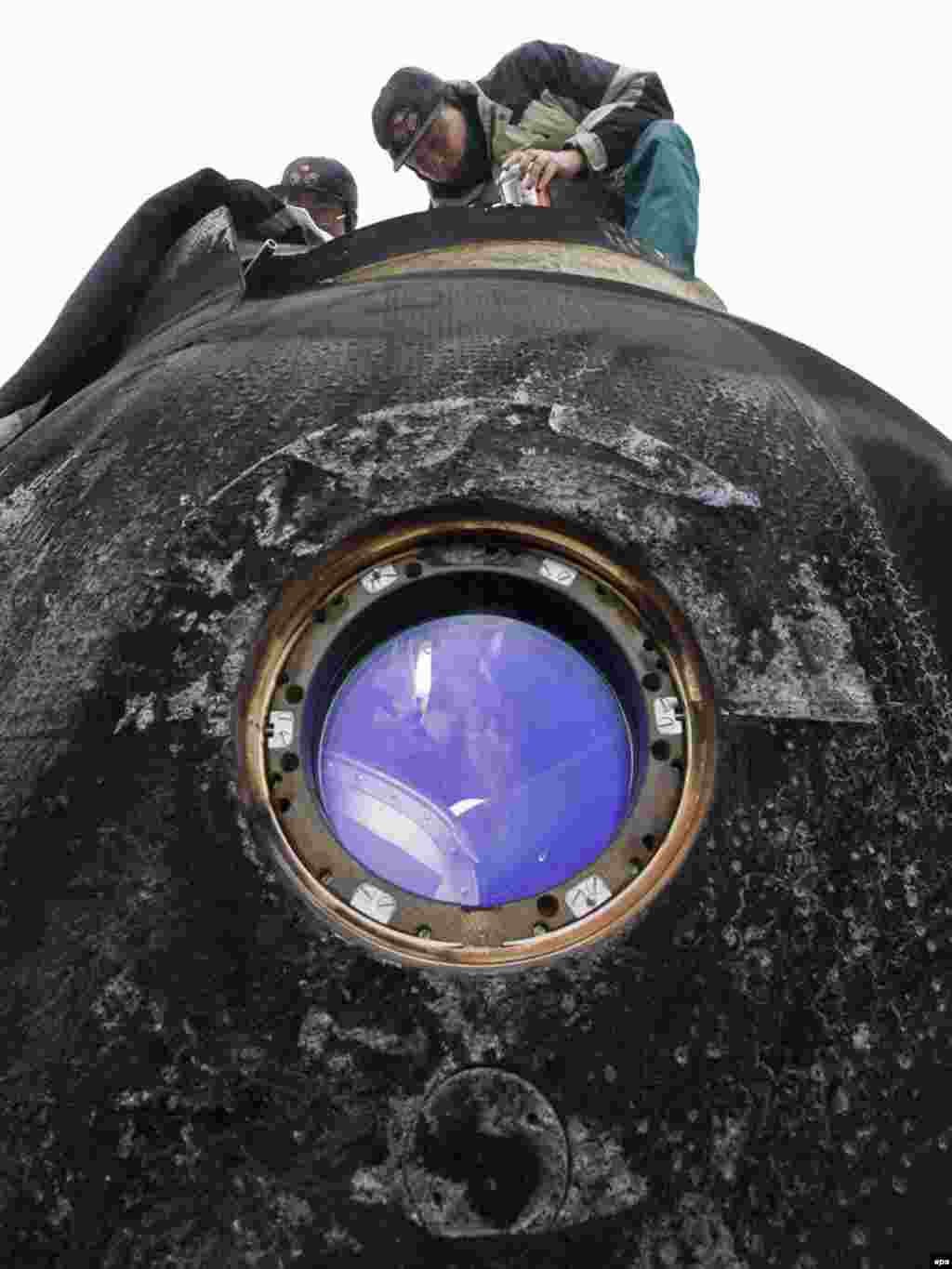 Russian specialists work on the Soyuz space capsule of the International Space Station. - The space capsule returned from the ISS and landed in northern Kazakhstan on December 1 carrying European Space Agency (ESA) astronaut Frank De Winne of Belgium, Russian cosmonaut Roman Romanenko, and Canadian astronaut Robert Thirsk. Photo by Shamil Zhumatov for epa