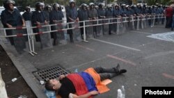 Armenia - A protester lies on the ground near riot police deployed on Marshal Bagramian Avenue, Yerevan, 26Jun2015.