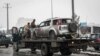 Afghan security forces carry a damaged vehicle from the site of a suicide attack that targeted the entrance gate of Marshal Fahim Military Academy in Kabul on February 11.