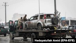 Afghan security forces carry a damaged vehicle from the site of a suicide attack that targeted the entrance gate of Marshal Fahim Military Academy in Kabul on February 11.