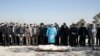 Mourners wearing face masks and gloves pray over the body of a former official in the Islamic Revolutionary Guards Corps, Farzad Tazari, who died on May 9 after being infected with the new coronavirus, at the Behesht-e-Zahra cemetery just outside Tehran on March 10.