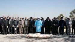 Mourners wearing face masks and gloves pray over the body of a former official in the Revolutionary Guard who died on March 9 after being infected with the new coronavirus, at the Behesht-e-Zahra cemetery just outside Tehran.