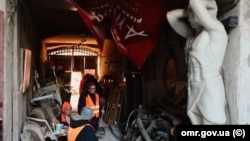 13 грудня 2025 року під час російської атаки постраждав житловий будинок в історичному центрі Одеси. На фото: комунальники очікують на відбій тривоги в арці, яка веде у двір постраждалого будинку