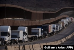 Грузовики в очереди у пограничной стены перед пунктом пересечения границы с Соединенными Штатами в коммерческом порту Отай в Тихуане. Штат Нижняя Калифорния, Мексика, 22 января 2025 года