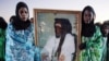 Women from the nomadic Tuareg tribe in traditional dress hold a portrait of Libyan leader Muammar Qaddafi during the 16th International Ghat Festival in southwest Libya in February 2010.