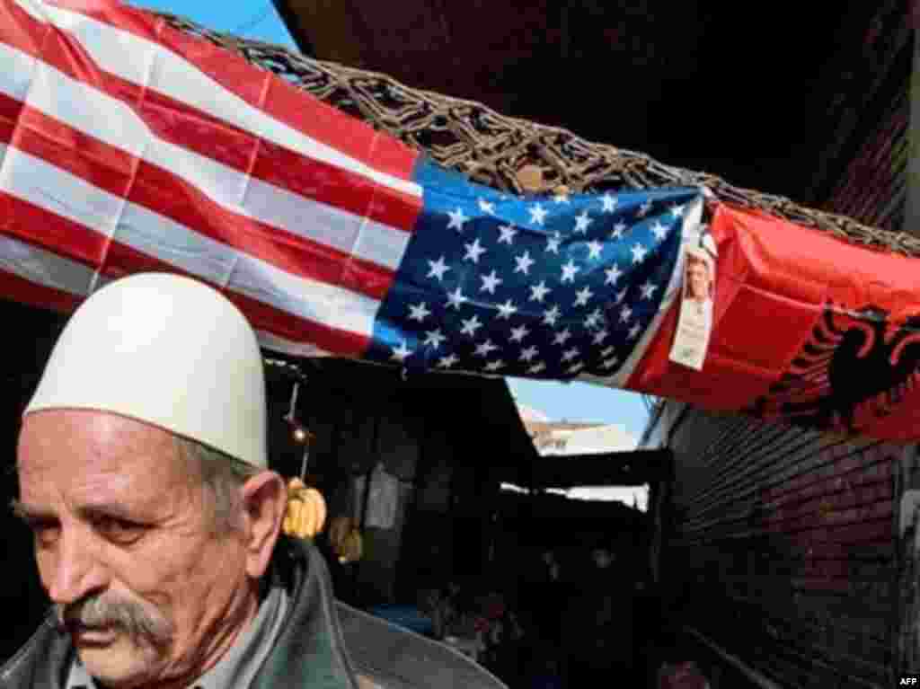 Kosova feston - SERBIA, Pristina : An ethnic Kosovo Albanian walks by a US and Albanian flag in an open-air market in Pristina on February 11, 2008. A declaration of Kosovo's independence by the end of this week looked increasingly likely Friday after Serbia said it had information the "illegal" move would happen on February 17.