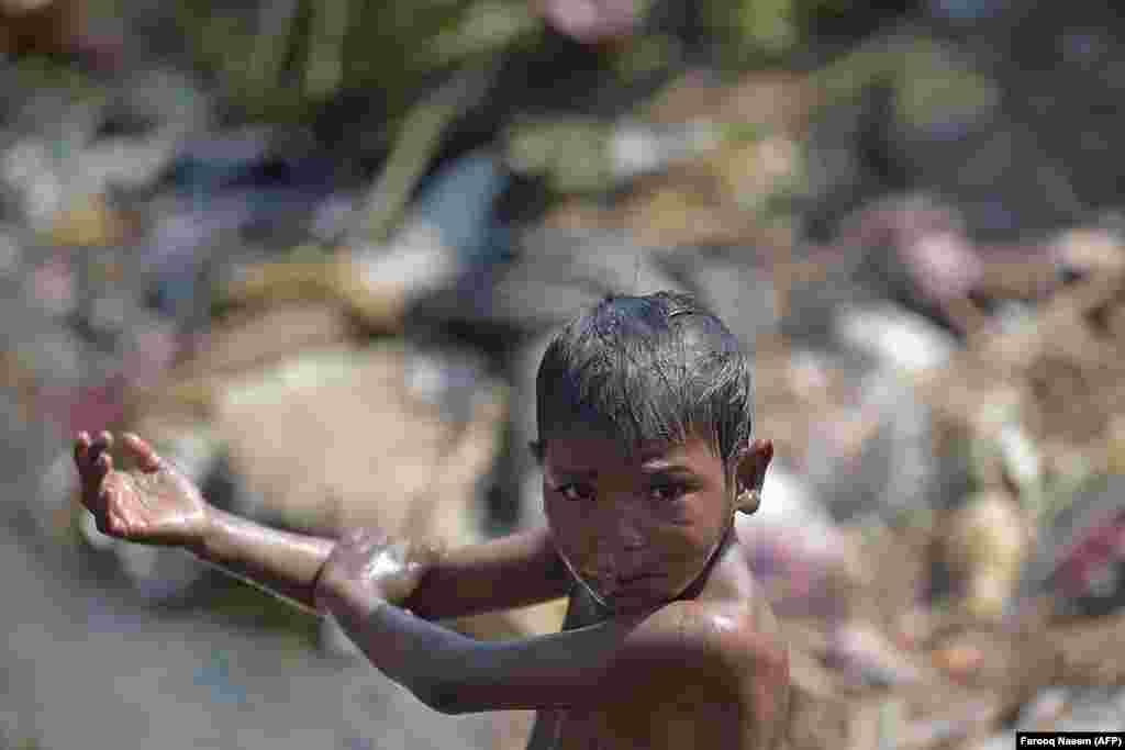 A boy takes a bath near a leaking water-supply pipeline in Rawalpindi, Pakistan. (AFP/Farooq Nareem)