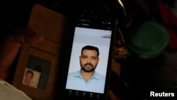 The brother of Shivanand Chaurasia, an Indian seafarer killed aboard the Palau-flagged tanker MT Settebello, looks over a photo of the slain sailor.