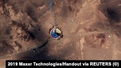 Сделанная со спутника фотография стартовой площадки космодрома имени имама Хомейни, откуда в небо поднимаются клубы дыма.
