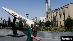 Një burrë ec pranë një maketi simbolik të një rakete iraniane, në një rrugë në Teheran në qershor.