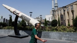 A man walks next to a symbolic mock-up of an Iranian missile, on a street in Tehran in June.