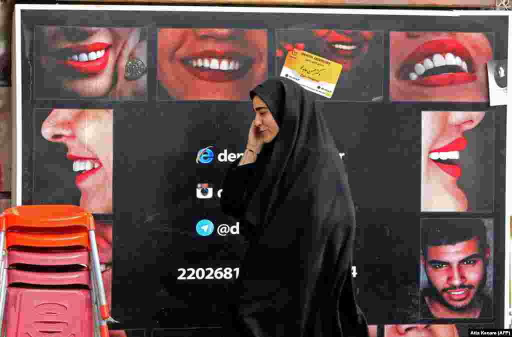 An Iranian woman walks past a billboard as she talks on the phone in the capital, Tehran. (AFP/Atta Kenare)