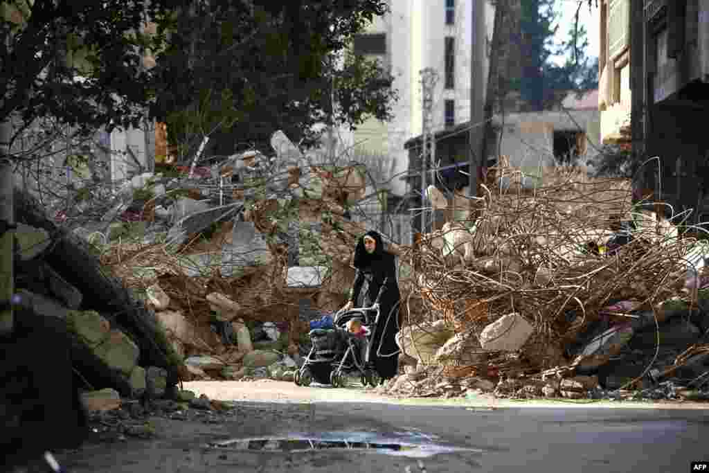 A woman walks pushing a baby stroller between the rubble of destroyed buildings in the besieged rebel bastion of Douma, Syria. (AFP/Abd Doumany)