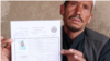 The father of a 15-year-old girl killed in the May 8 attack on Kabul's Sayed Al-Shuhada School holds his slain daughter's ID. "Masuma was both a son and a daughter for us," he said.