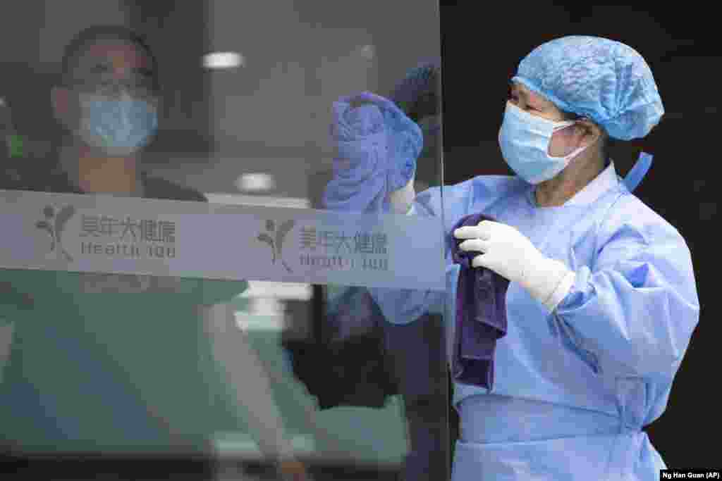 Працівниця миє скляні двері в медичному центрі для тестування на COVID-19 в Пекіні
