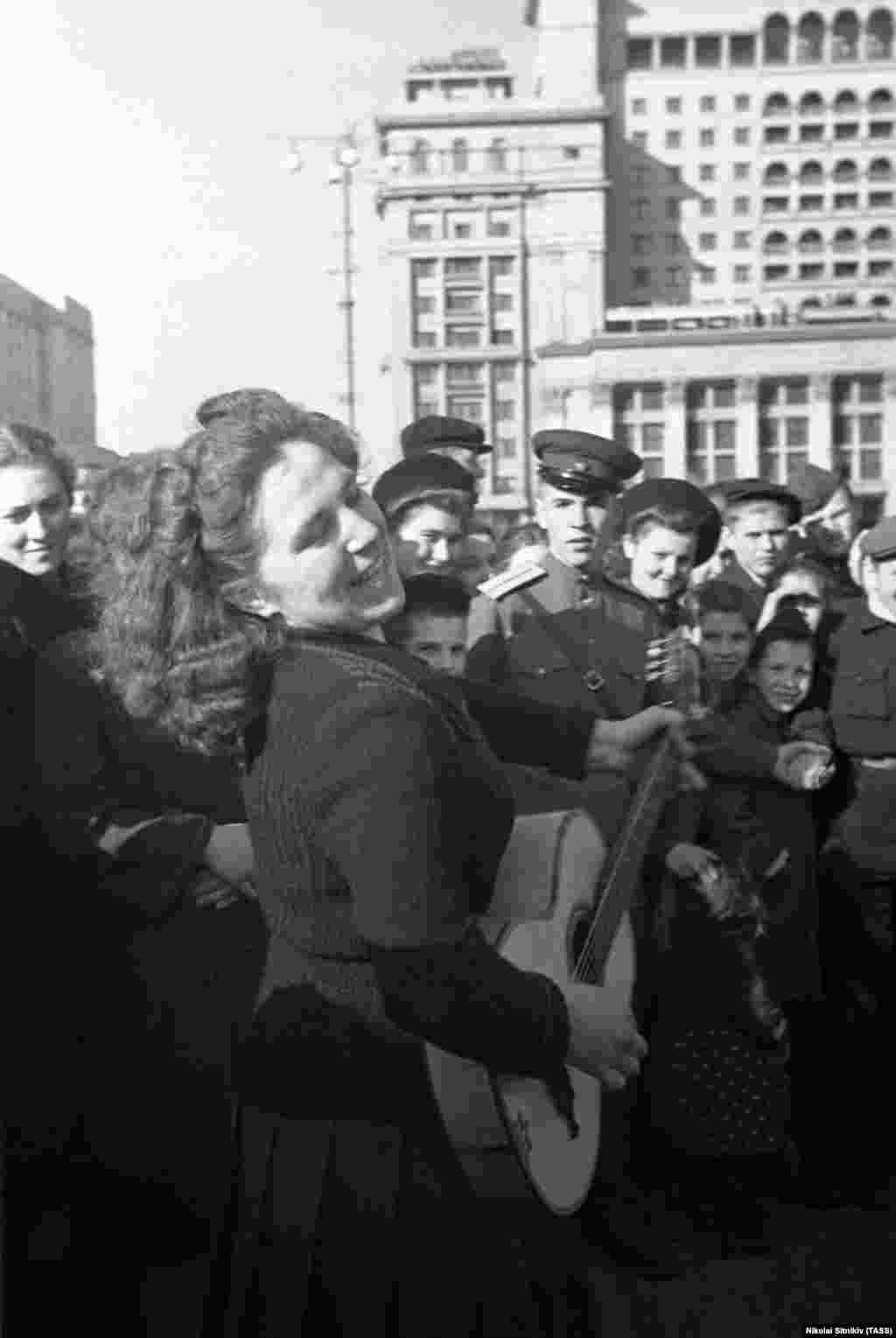 Поющая женщина в толпе в центре Москвы. В Советском Союзе празднования начались с наступлением 9 мая.