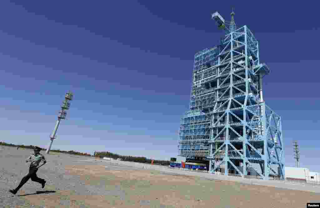 A soldier runs away from the launch pad holding China's Long March 2-F rocket. Three astronauts, including China's second female, blasted off into space on June 11 for a 15-day mission. (Reuters)