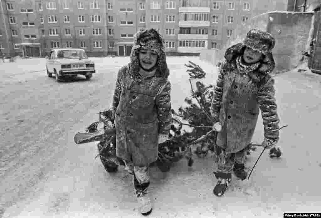 Children dragging their fir trees back to their apartment in 1994. After the collapse of the Soviet Union, Christmas was reinstated and is solemnly marked by Orthodox believers on January 7. &nbsp;