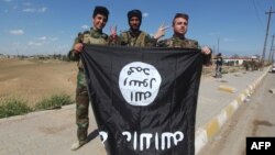 Iraqi Sunni and Shi'ite fighters pose for a photo with a captured Islamic State flag in Al-Alam, northeast of Tikrit, on March 17.