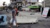 Men walk past at the site of a car bomb attack in Baghdad on August 26. 