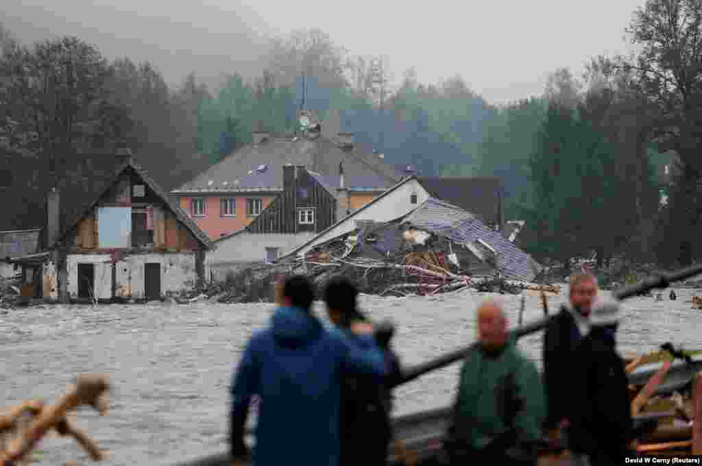 Onlookers watch floodwaters carrying debris past ruined houses in Jesenik on September 16. More than 12,000 people have been evacuated across the country, according to Czech Prime Minister Petr Fiala.