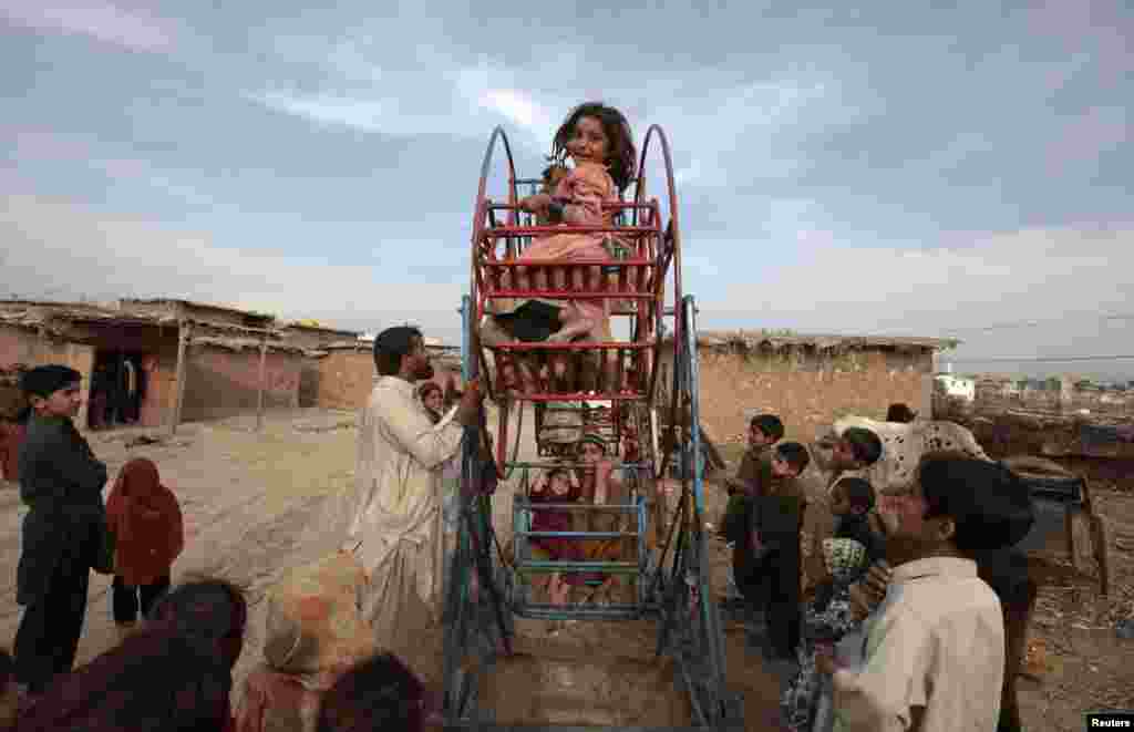 An Afghan girl smiles as she rides on a hand-operated Ferris wheel with other children in a slum on the outskirts of Islamabad, Pakistan. (Reuters/Faisal Mahmood)