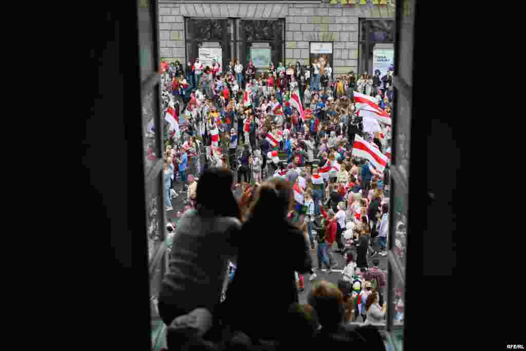 People take pictures of the protesters as they pass by their window in central Minsk.&nbsp;