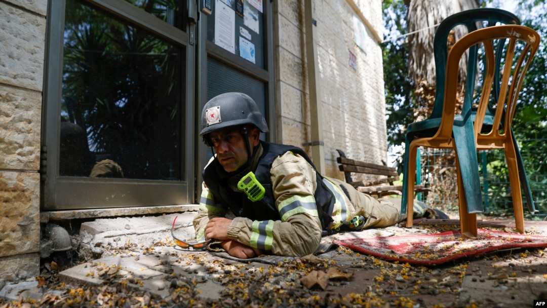 An Israeli firefighter takes cover in Kiryat Shmona, an evacuated city in northern Israel that frequently comes under rocket attacks launched by Hezbollah militants across the border in Lebanon.