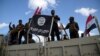 Shi'ite paramilitary fighters hold an Islamic State flag that they pulled down in Tikrit on March 31.