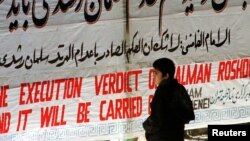 Иранский мальчик стоит перед транспарантом в Тегеранском университете с надписью «Приговор Салману Рушди к смертной казни будет приведен в исполнение». 14 февраля 1989 года британскому писателю Салману Рушди был издан религиозный смертный приговор, упомянутый в баннере.