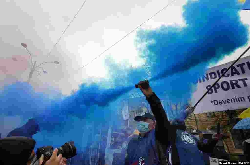 A Romanian worker of the PUBLISIND trade-union federation fires a flare during a protest in front of Romanian government headquarters in Bucharest. PUBLISIND represents workers in the fields of public administration, social assistance, penitentiaries, environment, and justice. Hundreds of people from all over the country gathered to protest against the economic measures adopted by the current government amid the coronavirus pandemic. (epa-EFE/Robert Ghement)