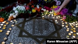 People lay flowers and place candles around the star of French-Armenian singer Charles Aznavour on the square named after him in Yerevan.