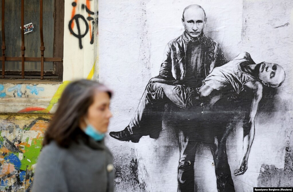 Një grua në Sofje kalon pranë një posteri që shfaq presidentin rus, Vladimir Putin, duke mbajtur trupin e tij, ndërsa pushtimi rus i Ukrainës vazhdon.