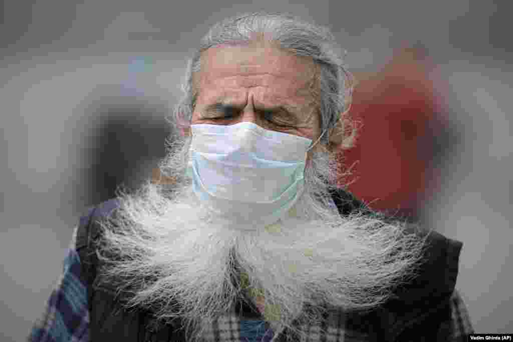 A man grimaces during a gust of wind at the Romanian Patriarchal Cathedral in Bucharest during a religious service ahead of the feast day of saints Constantine and Helena. (AP/Vadim Ghirda)