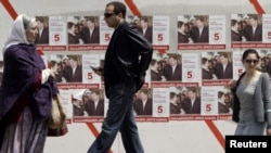 People walk past election posters in the center of Tbilisi