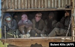 A truck carries men identified as Islamic State militants who surrendered to Kurdish-led Syrian Democratic Forces as they were being transported out of IS's last holdout of Baghouz in Syria's northern Deir Ezzor Province.