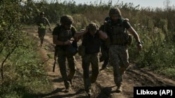 Ukrainian servicemen help to evacuate a wounded soldier at the front line near Bakhmut in the Donetsk region. 