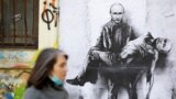 BULGARIA – A woman walks past a poster depicting Russian President Vladimir Putin holding his own body, as Russia's invasion of Ukraine continues, in Sofia, Bulgaria, March 28, 2022
